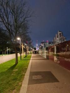 a sidewalk in a city at night with lights at North Greenwhich Homestay in London