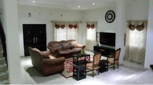 sala de estar con sofá de cuero y sillas en Villa at Grace, en Cape Coast