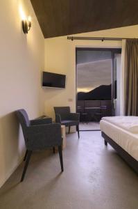 een slaapkamer met een bed, een stoel en een televisie bij Agriturismo B&B Caffè e Vino in Sondrio