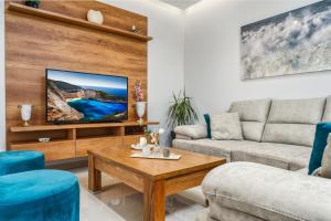 a living room with a couch and a tv at Valeria Luxury Villa - Private Pool - Nestled in Olive Groves Near Tsilivi Beach in Planos
