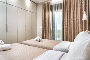 two beds in a bedroom with a window at Valeria Luxury Villa - Private Pool - Nestled in Olive Groves Near Tsilivi Beach in Planos +89 photos