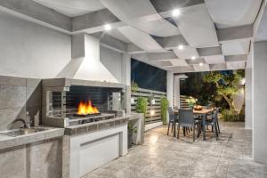 an outdoor kitchen with a fireplace and a table with chairs at Valeria Luxury Villa - Private Pool - Nestled in Olive Groves Near Tsilivi Beach in Planos