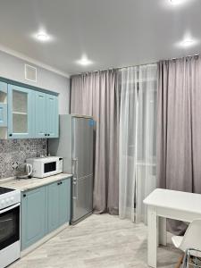 a kitchen with blue cabinets and a stainless steel refrigerator at Новый ЖК на Байзакова in Pavlodar