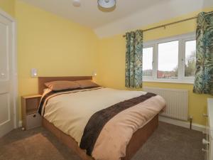 a bedroom with a large bed and two windows at Lambs Fold in Malton