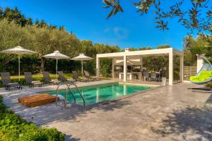 a swimming pool with chairs and umbrellas next to a house at Valeria Luxury Villa - Private Pool - Nestled in Olive Groves Near Tsilivi Beach in Planos