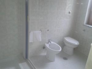 La salle de bains blanche est pourvue de toilettes et d'un lavabo. dans l'établissement Le Acacie, à Castellammare di Velia