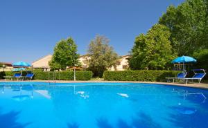 une grande piscine avec deux chaises bleues et des parasols dans l'établissement Le Acacie, à Castellammare di Velia