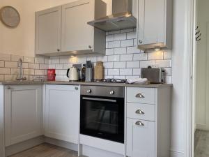 a kitchen with white cabinets and a stove top oven at Apartment 2 St Georges in Cheltenham