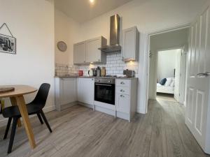 a kitchen with white cabinets and a table and a dining room at Apartment 2 St Georges in Cheltenham