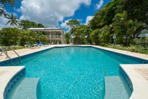 a swimming pool with chairs and a house at La Hacienda Bellevue in Bridgetown