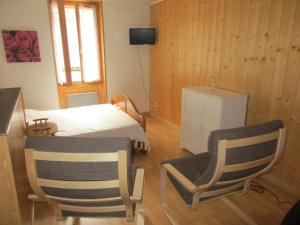 a room with two chairs and a bed and a television at Au P'tit Grillon in Salins-les-Bains