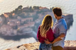 a young man and woman standing on a ledge overlooking the city at Alessandra Apartments in Sveti Stefan
