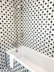 a white bath tub in a bathroom with black and white tiles at Hôtel La Tour Intendance in Bordeaux