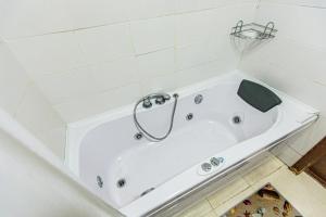 a white bath tub in a white tiled bathroom at Maulenova 32.36 kv41 in Almaty