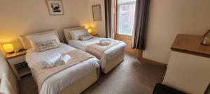Una habitación de hotel con dos camas y una ventana. en Criffel Cottage, en Dumfries