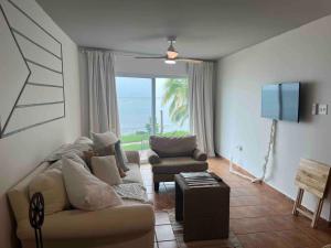 Una sala de estar con un sofá, una silla y un televisor. en Beachfront Luxury Apartment, en Aguada