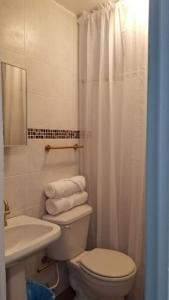 a white bathroom with a toilet and a sink at Beachfront Luxury Apartment in Aguada