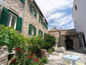 a stone building with green shutters and a table and chairs at Malin Guesthouse in Skradin +30 photos