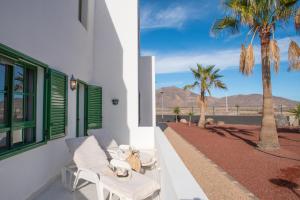 a balcony with a chair and a palm tree at CASA PAZ - COZY 2 BEDROOM APARTMENT CLOSE TO DORADA BEACH in Playa Blanca
