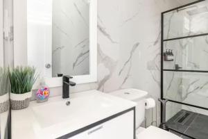 a white bathroom with a sink and a mirror at Encanto house with king bed in Isabela