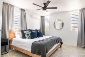 Schlafzimmer mit einem Bett mit blauen Kissen und einem Deckenventilator in der Unterkunft Encanto house with king bed in Isabela