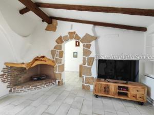 uma sala de estar com uma lareira de pedra e uma televisão em Villa Lilium em Cannigione