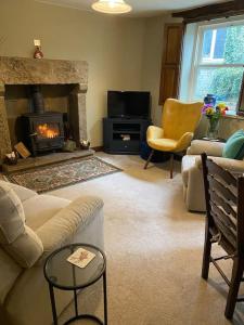 ein Wohnzimmer mit einem Sofa und einem Kamin in der Unterkunft Peaceful cottage Peak District, nr Bakewell in Buxton