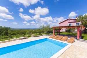 a swimming pool with chairs and a house at Villa Vale in Labin