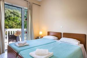 a bedroom with two beds and a large window at Villa Lourdas Beach by Villa Plus in Trápeza +18 photos