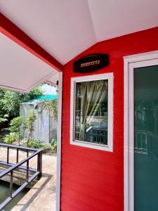 a red house with a window on the side at MrT Riverside Sampran มิสเตอร์ที โฮมสเตย์-ทองกวาว in Sam Phran