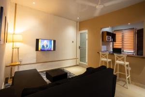 sala de estar con sofá negro y cocina en Furnished 1 Bedroom Apartment in Accra, en Accra