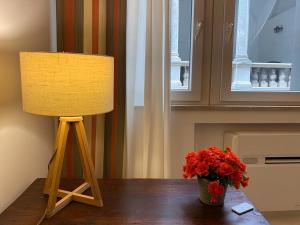 a lamp and a vase of red flowers on a table at Loggiato Palazzo San Matteo in Palermo