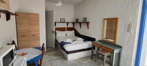 ein kleines Schlafzimmer mit einem Bett und einem Spiegel in der Unterkunft Oleander's Garden Traditional Cretan Cottage in Ferma