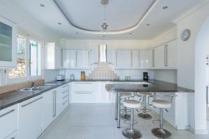 a kitchen with white cabinets and a island with bar stools at Villa Panorama Andrea by Villa Plus in Ágios Ilías