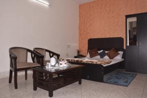 a bedroom with a bed and a table and a chair at Atithi Ashray in Patna