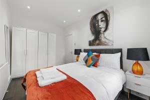 a bedroom with a large bed with a portrait on the wall at Stunning 1 & 2 bedroom Apartments Central London ZONE 1 in London