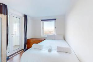 a bedroom with a white bed and a window at Modern 2BD flat in Bethnal Green- 10 min to tube in London