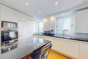cocina con armarios blancos y encimera negra en Modern 2BD flat in Bethnal Green- 10 min to tube en Londres