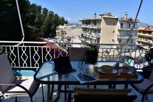a table on a balcony with a view of a city at Igoumenitsa Retiré Apartment in Igoumenitsa