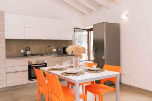 a kitchen with a white table and orange chairs at GOMES COMFORT HOUSE in Valeggio sul Mincio
