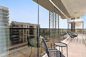 Un balcón con sillas y mesas en un edificio en Silkhaus Luxurious 1 BDR Next to Golf Course en Abu Dabi