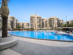 een groot zwembad met hoge gebouwen op de achtergrond bij Silkhaus Luxurious 1 BDR Next to Golf Course in Abu Dhabi