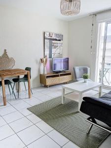 sala de estar con TV y mesa en CABOURG - 2 PIÈCES avec Balcon et parking- Hyper Centre et Plage, en Cabourg