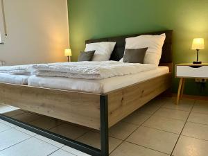 a bedroom with a wooden bed with white sheets and pillows at Ferienapartments Eifel Stay in Lissendorf +8 photos