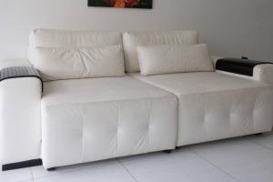 un sofá blanco sentado en una sala de estar en Marisia, en Guarujá