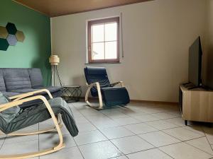 a living room with a couch and a tv at Ferienapartments Eifel Stay in Lissendorf