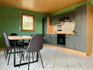 a kitchen with green walls and a table and chairs at Ferienapartments Eifel Stay in Lissendorf