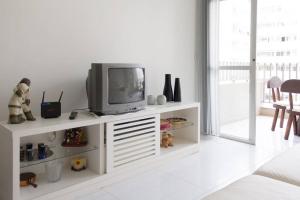 a living room with a tv on a white entertainment center at Marisia in Guarujá