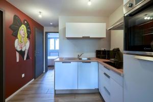 Una cocina con gabinetes blancos y un cuadro en la pared. en L'ALSACIEN Centre Ville 2 chambres et Terrasse, en Colmar