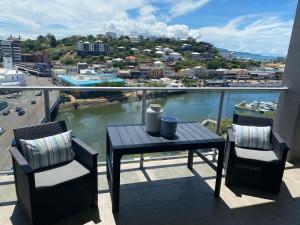 a table and chairs on a balcony with a view of a river at Apartment 1102 | 11th Floor River & Stadium Views in Townsville